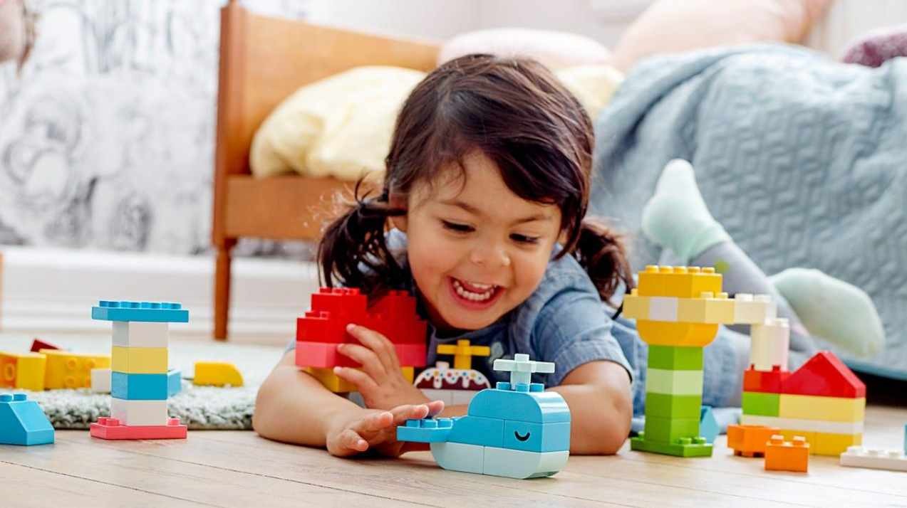 malé dítě si hraje s LEGO DUPLO a staví z velkých kostek