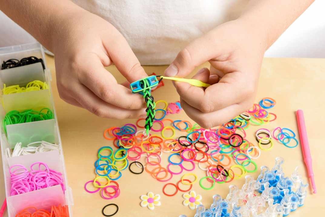 dítě tvoří náramek z barevných gumiček